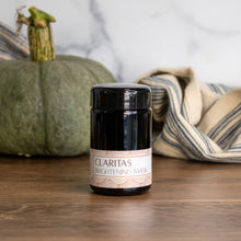 Claritas Brightening Mask with a green pumpkin and striped linens in the background