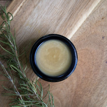 Top down view of Anam Cara Restorative Balm with a sprig of Rosemary