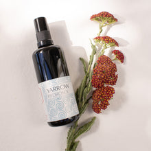 Bottle of Yarrow Hydrosol on a white background with fresh yarrow flowers