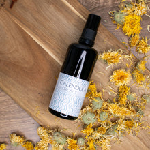 Calendula Hydrosol on wooden background with dried calendula flowers 