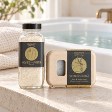 Seagrape bath soak and Lavender Orange soap beside a bathtub; styling props not included.