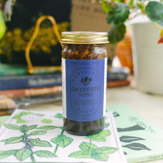 Jar of honey with a label on a table with plants in the background