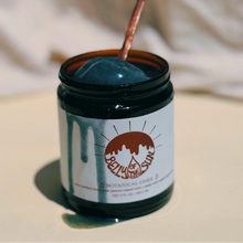 Jar of blue ghee with a spoonful being taken, against a neutral background