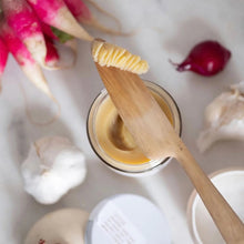 wooden knife scooping ghee out of the jar
