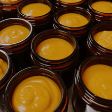 Multiple small jars filled with a yellow cream or paste.